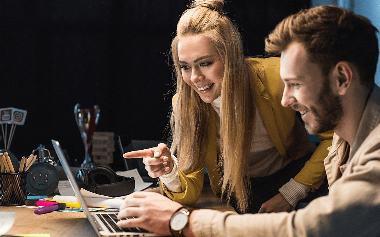 A man and a woman looking at a laptop screen