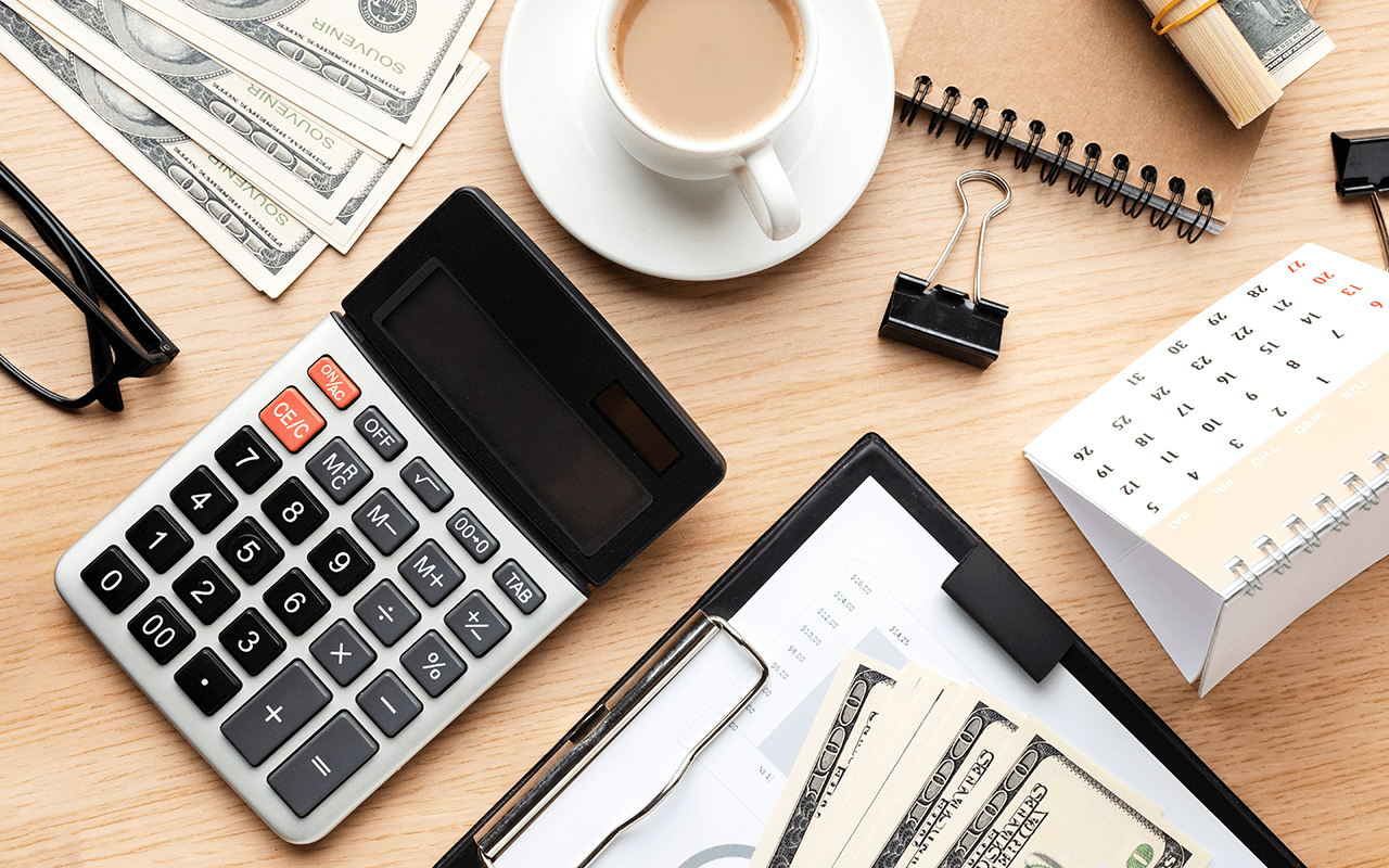 A wooden table topped with a calculator and a cup of coffee